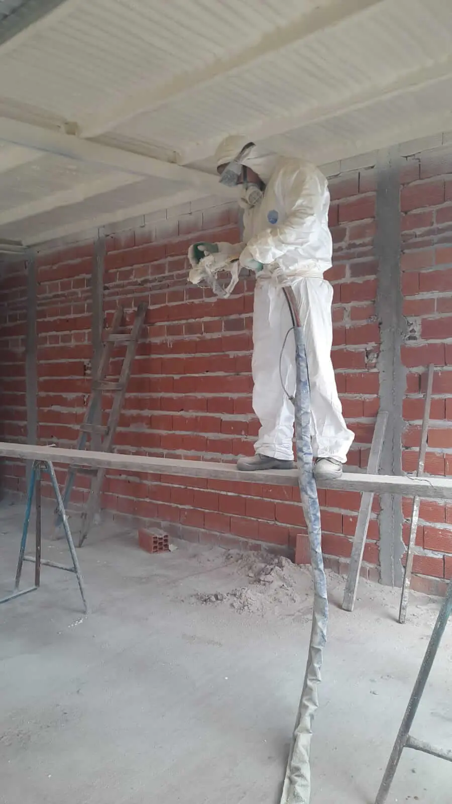 Operario de FEYSA con equipo de protección completo proyectando poliuretano expandido sobre un cielorraso.
